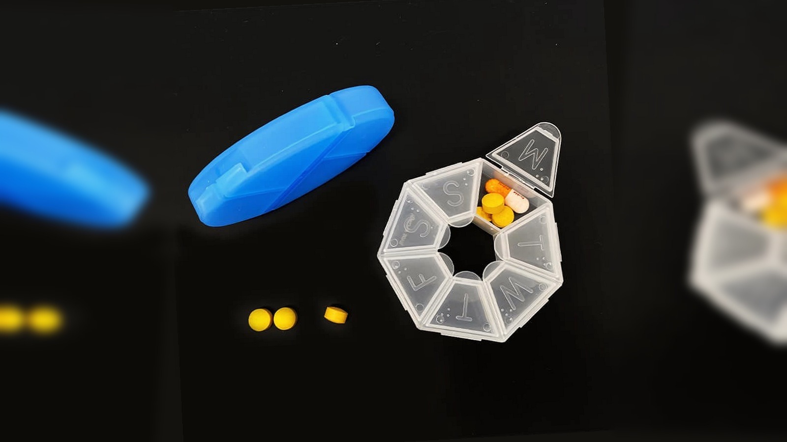 transparent weekly braille pill box with detached blue lid and raised day-letter compartments